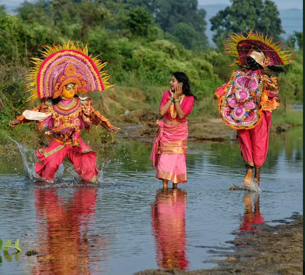 Chhau folk dancers mid-motion through a stream